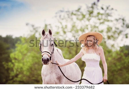 Woman in white dress walking with horse in green countryside