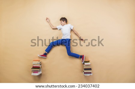 Happy boy is playing with group of books in studio