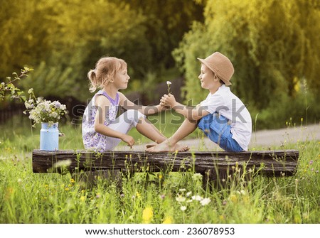 Cute boy and girl in love. They sitting on bench at sunset.