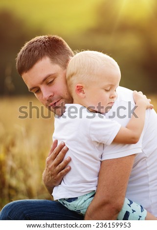 Young father and son enjoying life together. They are hugging outside in nature