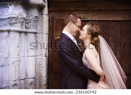 Wedding couple of bride and groom standing by old stone chapel.