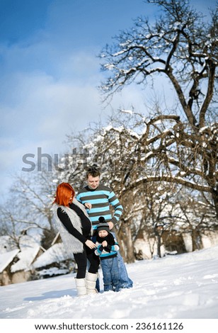 Happy parents with child having fun outside in snow