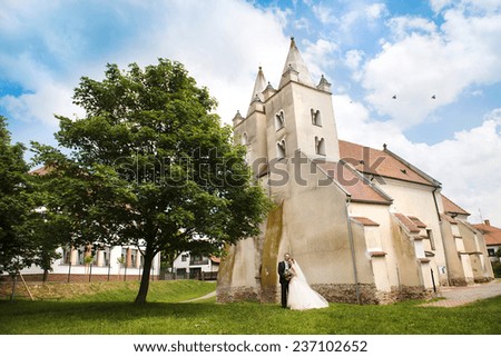 Wedding couple of bride and groom standing by the church.