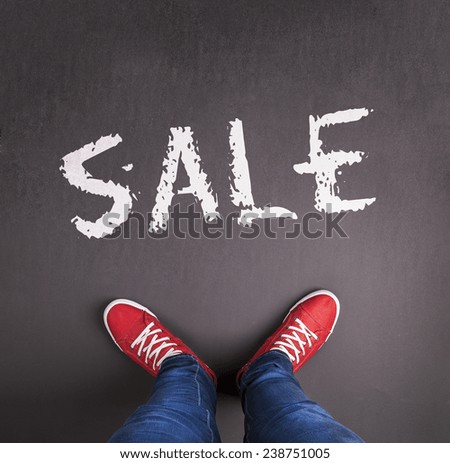 Sale concept with red sneakers and white paint text on black floor