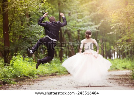 Wedding couple - bride and groom - running down the road