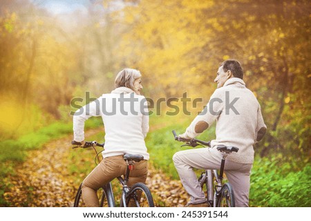 Active seniors riding bikes in autumn nature. They having romantic time outdoor.