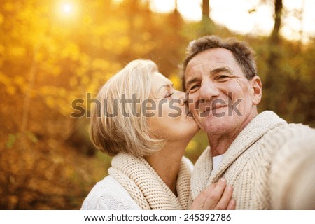 Active seniors taking selfies of them having fun outside in the autumn forest