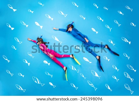 Children scuba diving deep in the sea. Studio shot on a blue background.