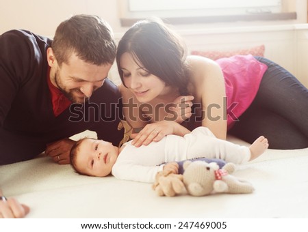 Happy young parents with their little baby girl at home