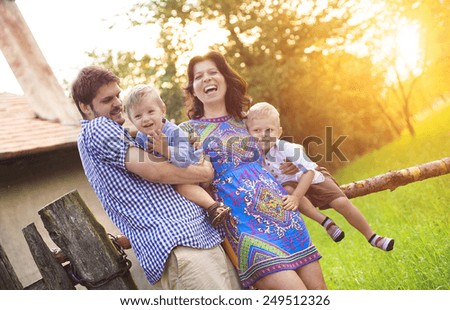 Happy young family spending time together and having fun in front of an old countryside house.