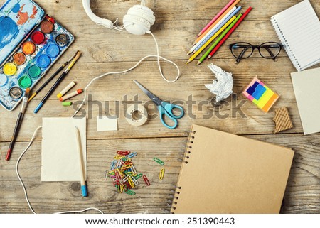 Desk of an artist with lots of stationery objects. Studio shot on wooden background.
