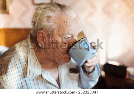 Senior man sitting on a bed and drinking water