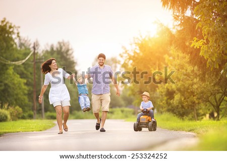 Happy young family having fun outside on the street of a village
