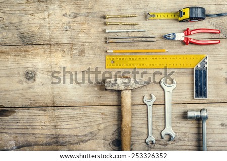 Desk of a carpenter with a hammer and two nails. Studio shot on a wooden background.