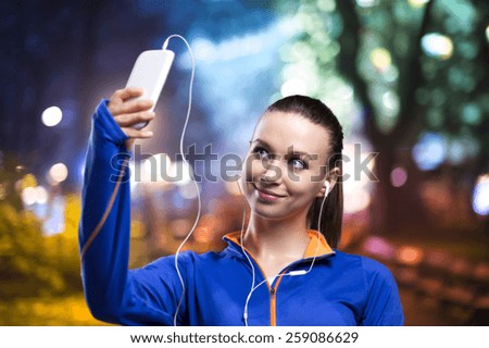 Young woman jogging at night in the city taking selfie