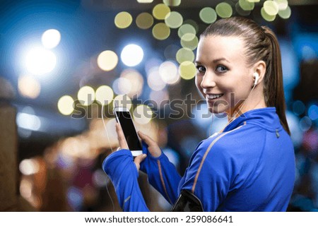 Young woman jogging at night in the city while listening music