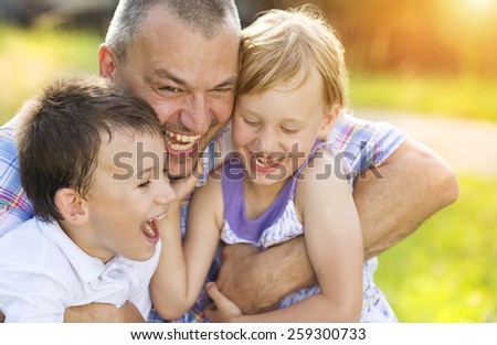 Father with his two children spending time together outside in green nature.