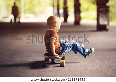 Cute little boy with his skateboard on a walk in the city
