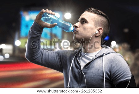 Young sportsman jogging in the night city with a water bottle