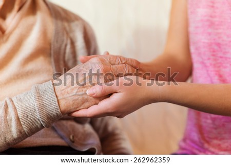 Unrecognizable grandmother and her granddaughter holding hands.