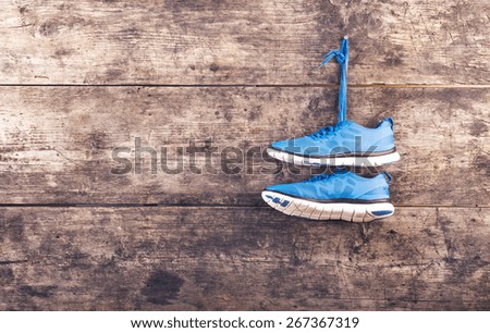 Pair of running shoes hang on a nail on a wooden fence background