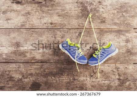 Pair of running shoes hang on a nail on a wooden fence background