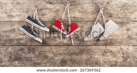 Three pairs of sports shoes hang on a nail on a wooden fence background