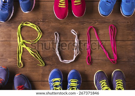 Six pairs of running shoes and shoelaces run sign on a wooden floor background