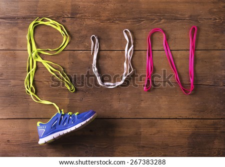 Running shoe and shoelaces run sign on a wooden floor background