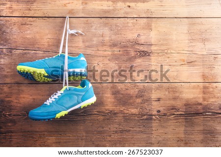 Pair of sports shoes hang on a nail on a wooden fence background