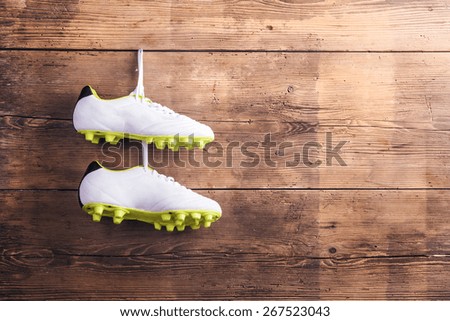 Pair of football shoes hang on a nail on a wooden fence background