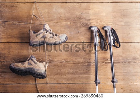 Nordic walking poles and hiking shoes hang on a wooden fence background