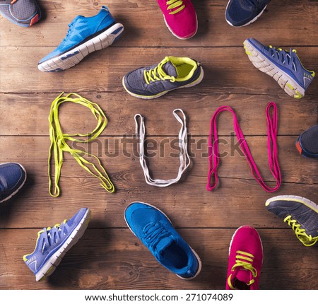 Various running shoes and shoelaces run sign on a wooden floor background