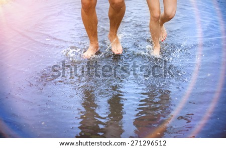 Unrecognizable woman and man walking barefoot through a puddle