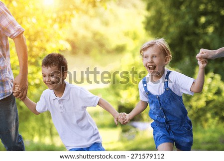 Happy little girl and boy having fun with their parents in green nature.