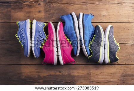 Four pairs of various running shoes laid on a wooden floor background