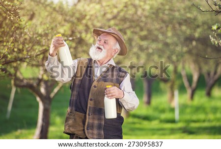 Senior farmer with milk bottles outside in green nature