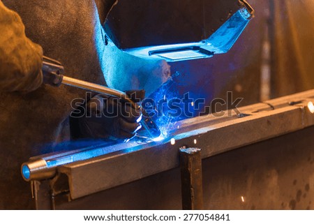 Young man with protective mask welding in a factory