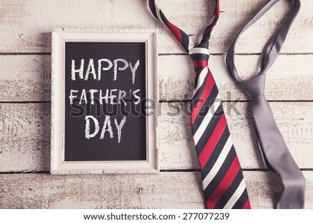 Rectangle picture frame with Happy fathers day sign and two ties laid on wooden floor backround.
