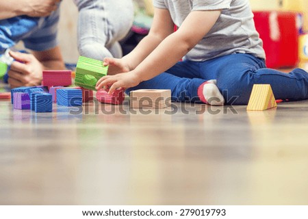 Young hipster playing with his daughters on a floor
