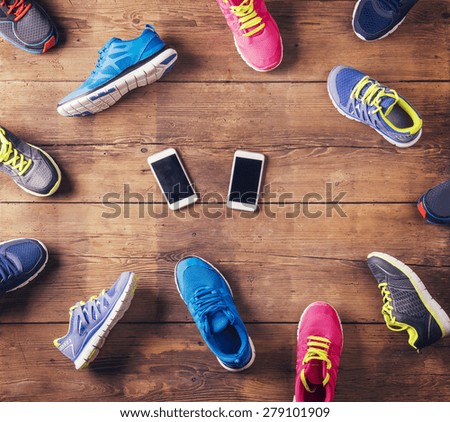 Various running shoes and two smart phones laid on a wooden floor background