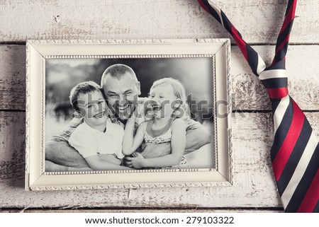 Picture frame with family photo and colorful tie laid on wooden backround.