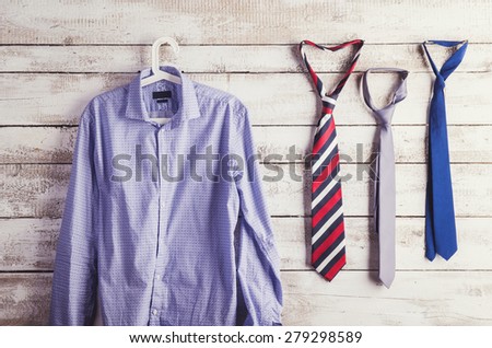 Fathers day composition of shirt and three ties hang on wooden wall background.