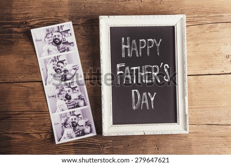 Picture frame with Happy fathers day sign and instant photos on wooden background.