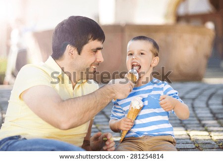 Father and son enjoying ice cream outside in a park