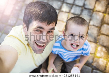 Father and son enjoying ice cream outside in a park