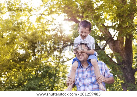Happy father with his son spending time together outside in green nature.