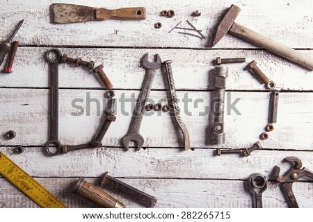 Desk of a carpenter with Dad sign and various tools. Studio shot on a wooden background.