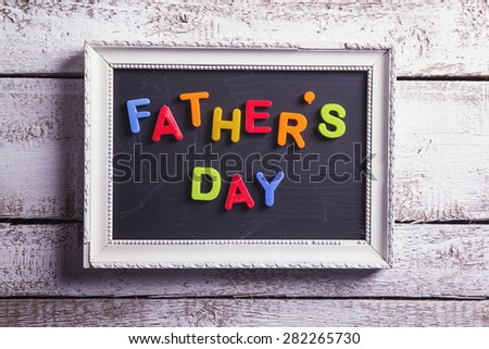 Picture frame with Fathers day sign laid on wooden floor background.