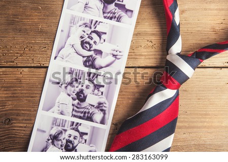 Pictures of father and daughter and colorful tie laid on wooden floor backround.